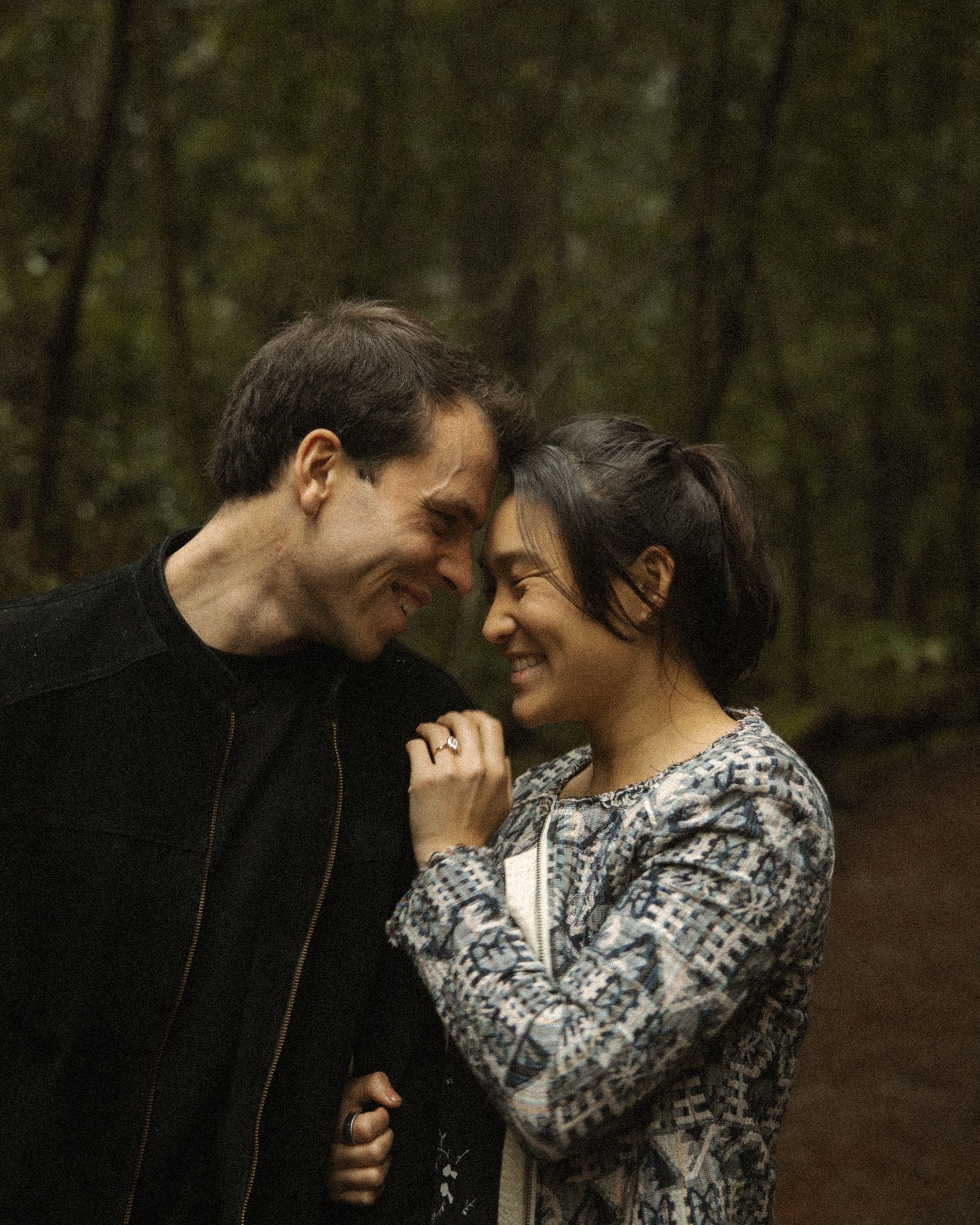 Laura and Eric, foreheads together in the forest